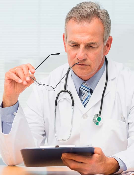 мужчина врач с планшетом в руке сидит за столом